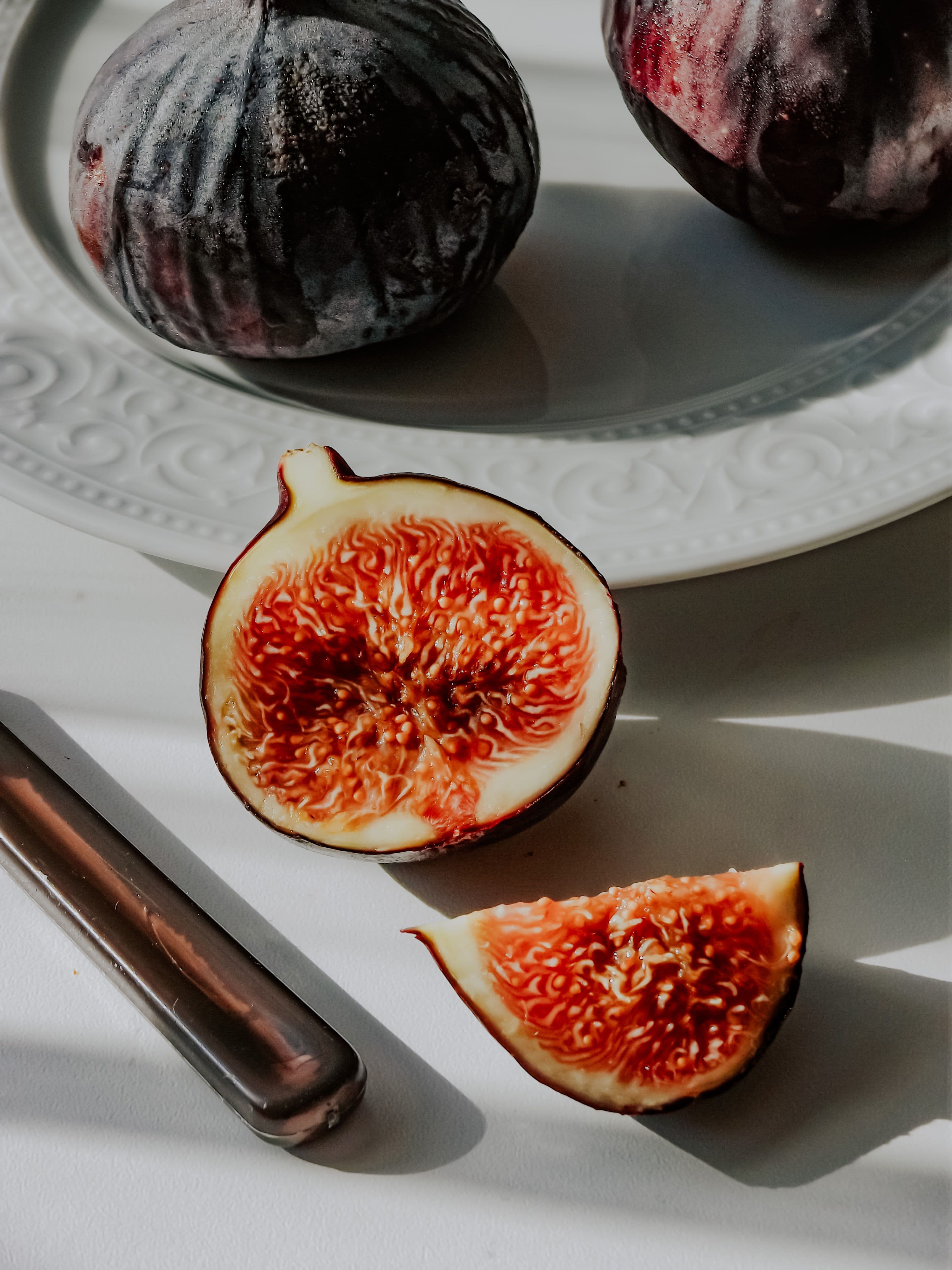 A single fig on a wooden board with a small knife beside it