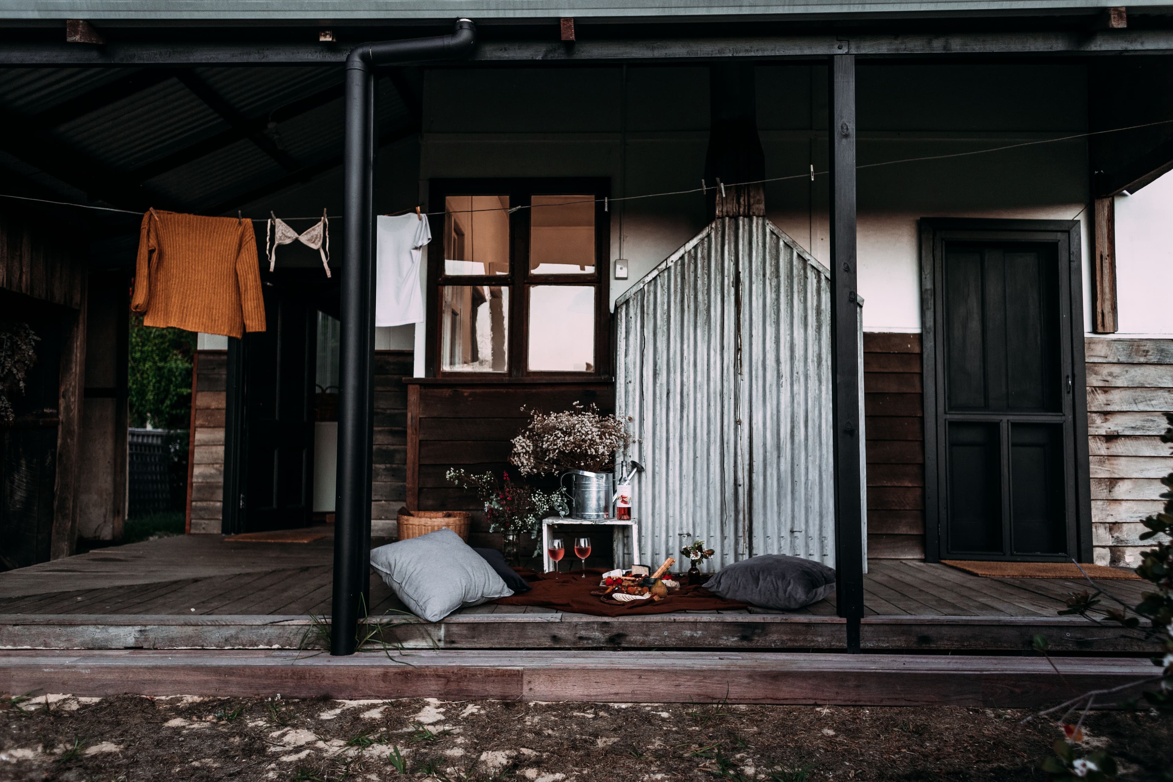 Wet boots, a coat on a hook and a towel by a back door on a rainy morning