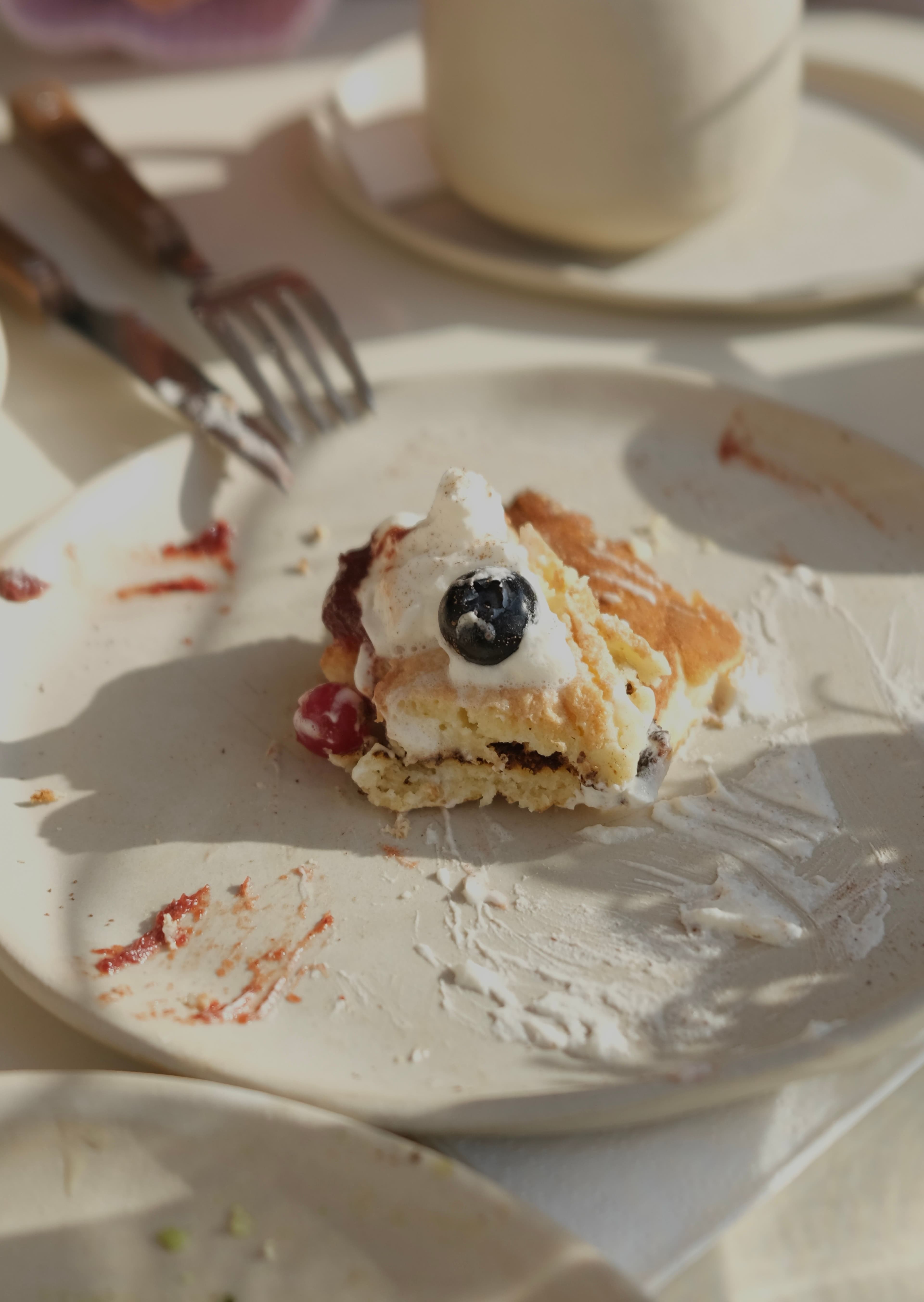 A wooden board at the end of the table holding stacked plates and an empty bottle