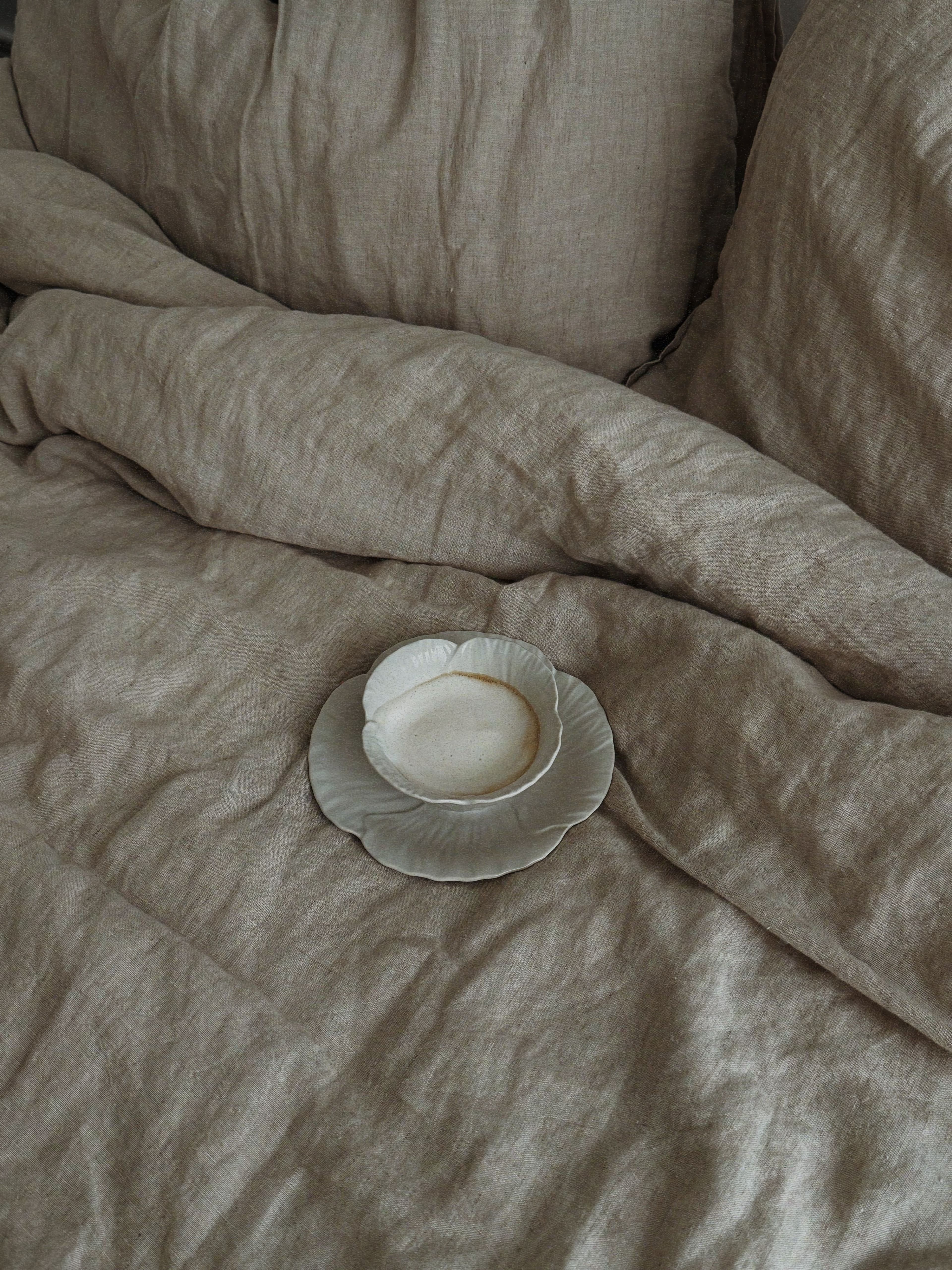 A slightly untidy, lived-in bed dressed in linen
