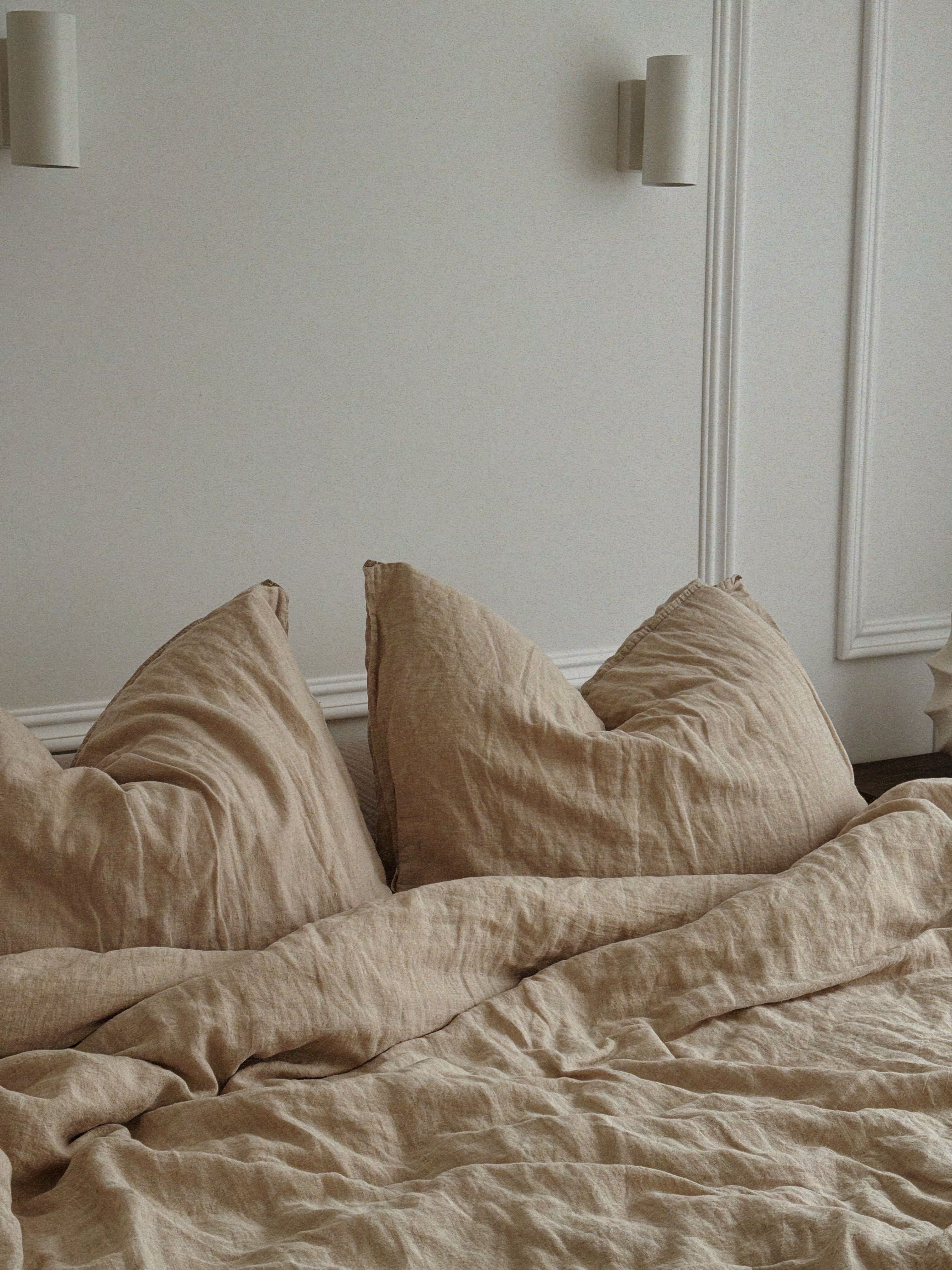 Natural linen sheets loosely arranged on a bed in soft morning light