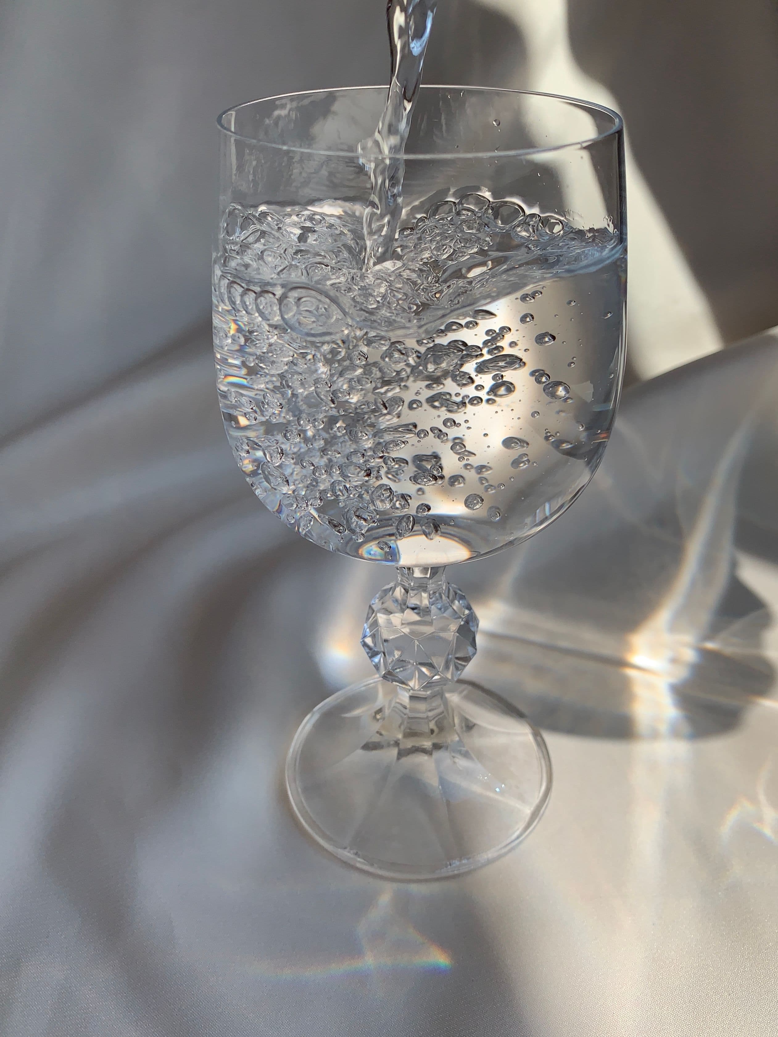 Close detail of a crystal glass held up to the light, showing weight and cut