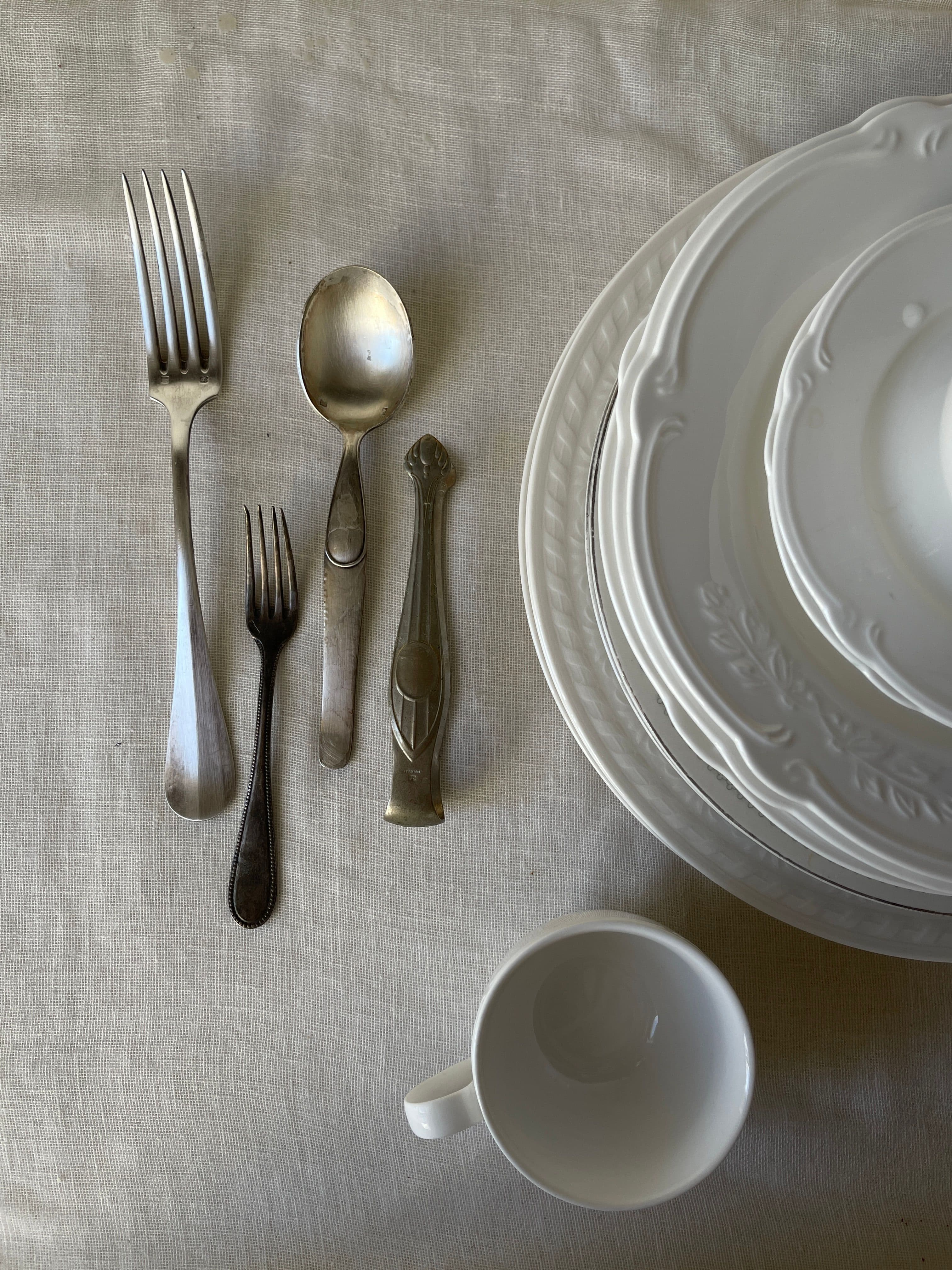 A well-used silver spoon and a softened linen napkin, the silver showing fine marks of use
