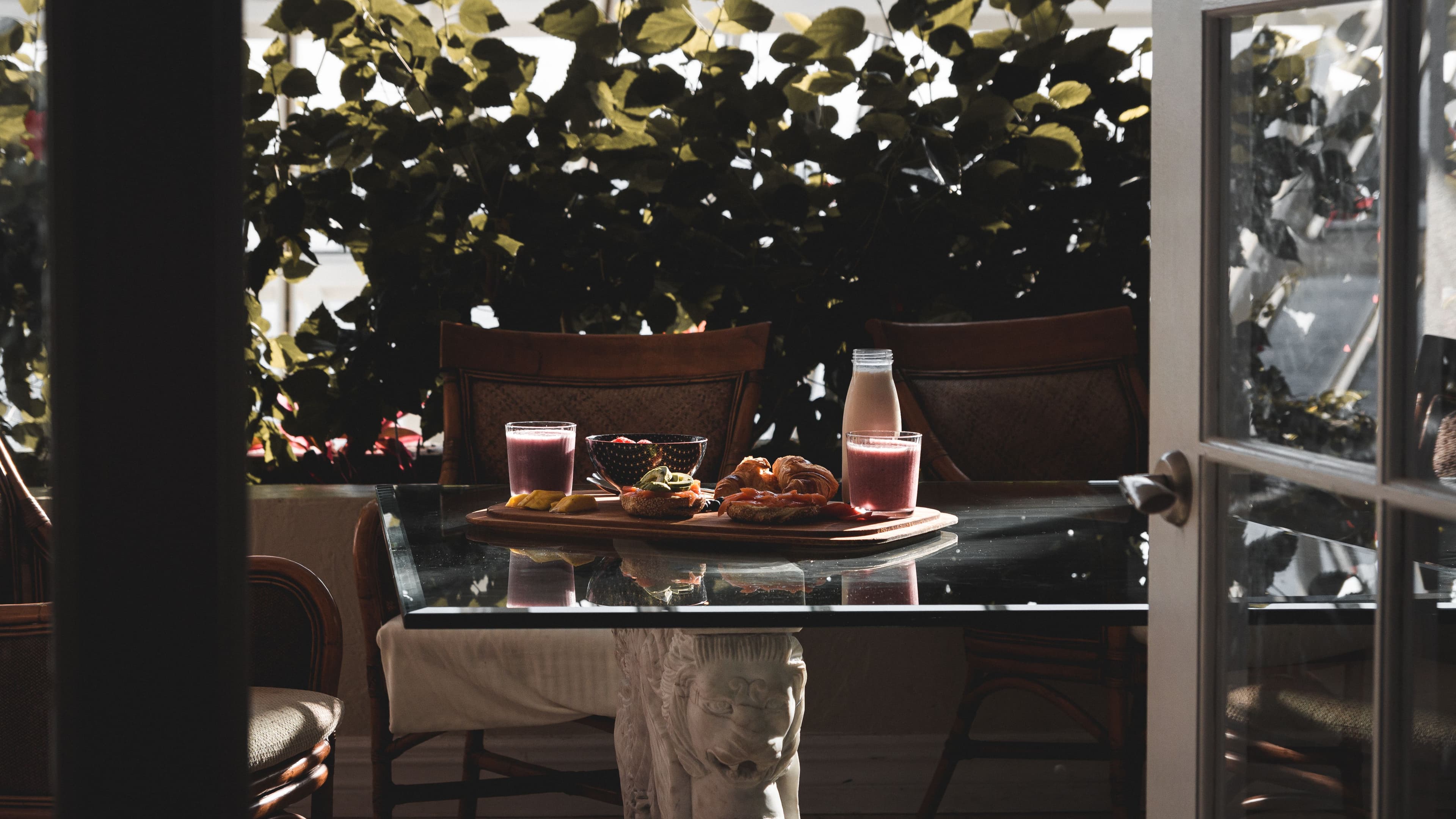 A table late in a long meal, glasses half-full and the cloth creased, in afternoon light