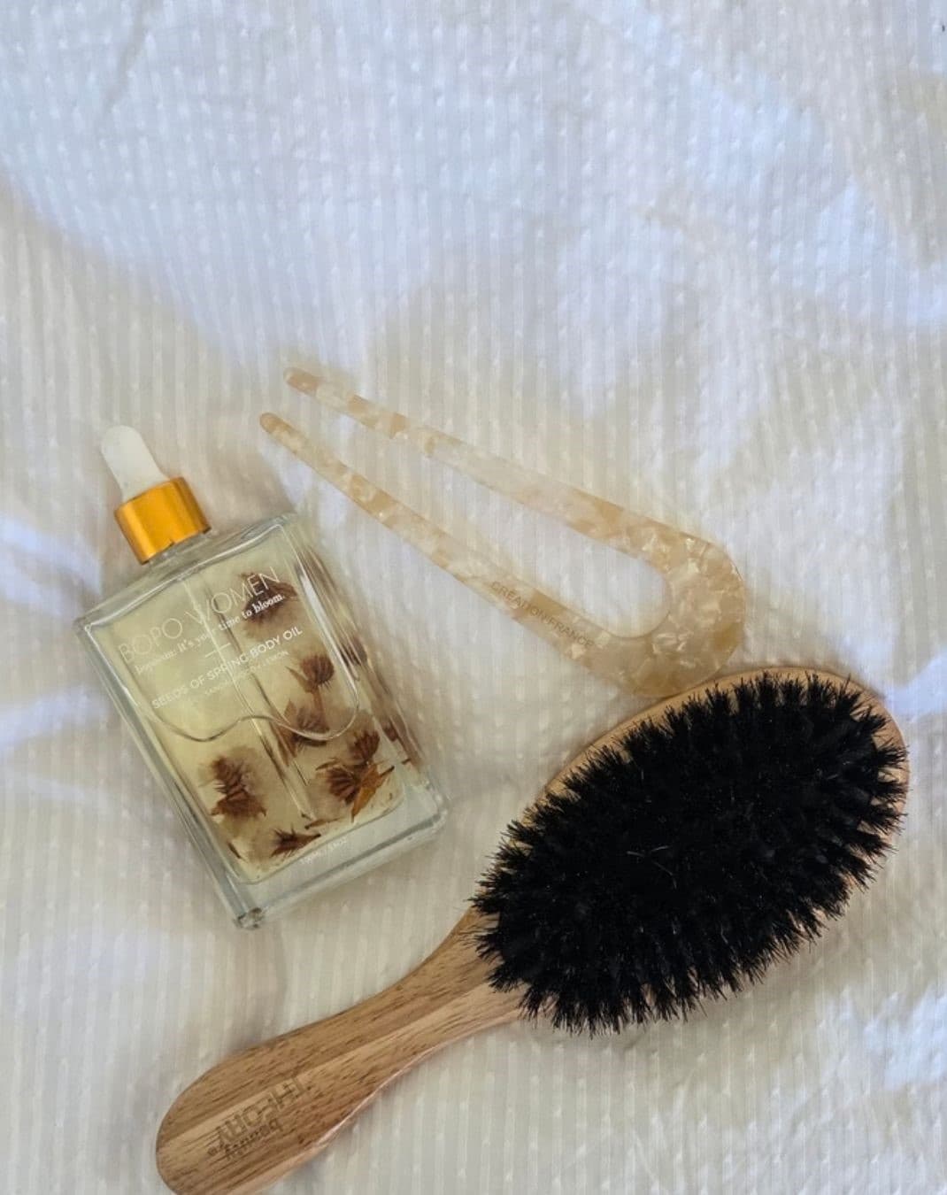 A wooden round hairbrush resting on a quiet dressing table in natural morning light