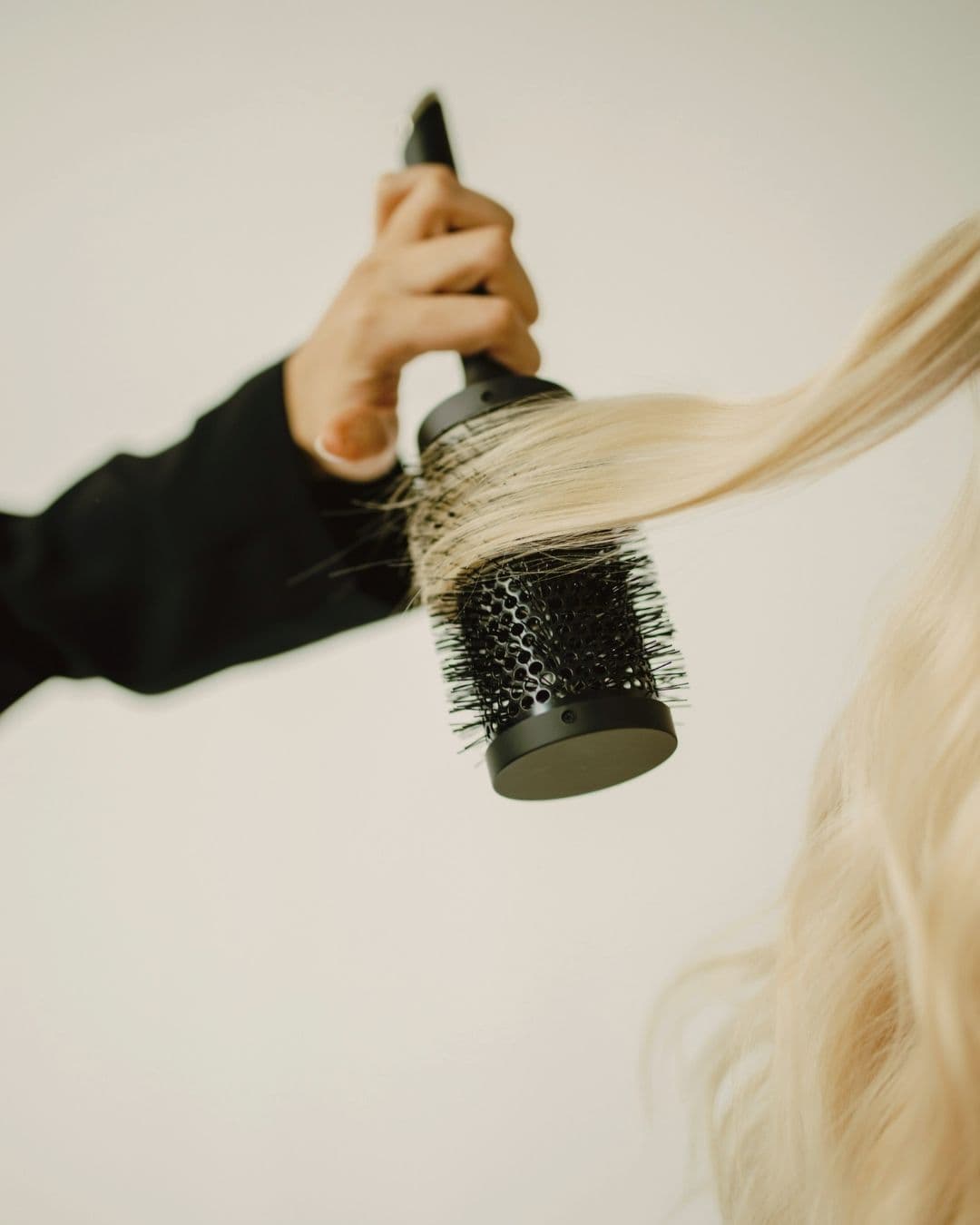 Round hairbrush being used to shape hair during a blowout