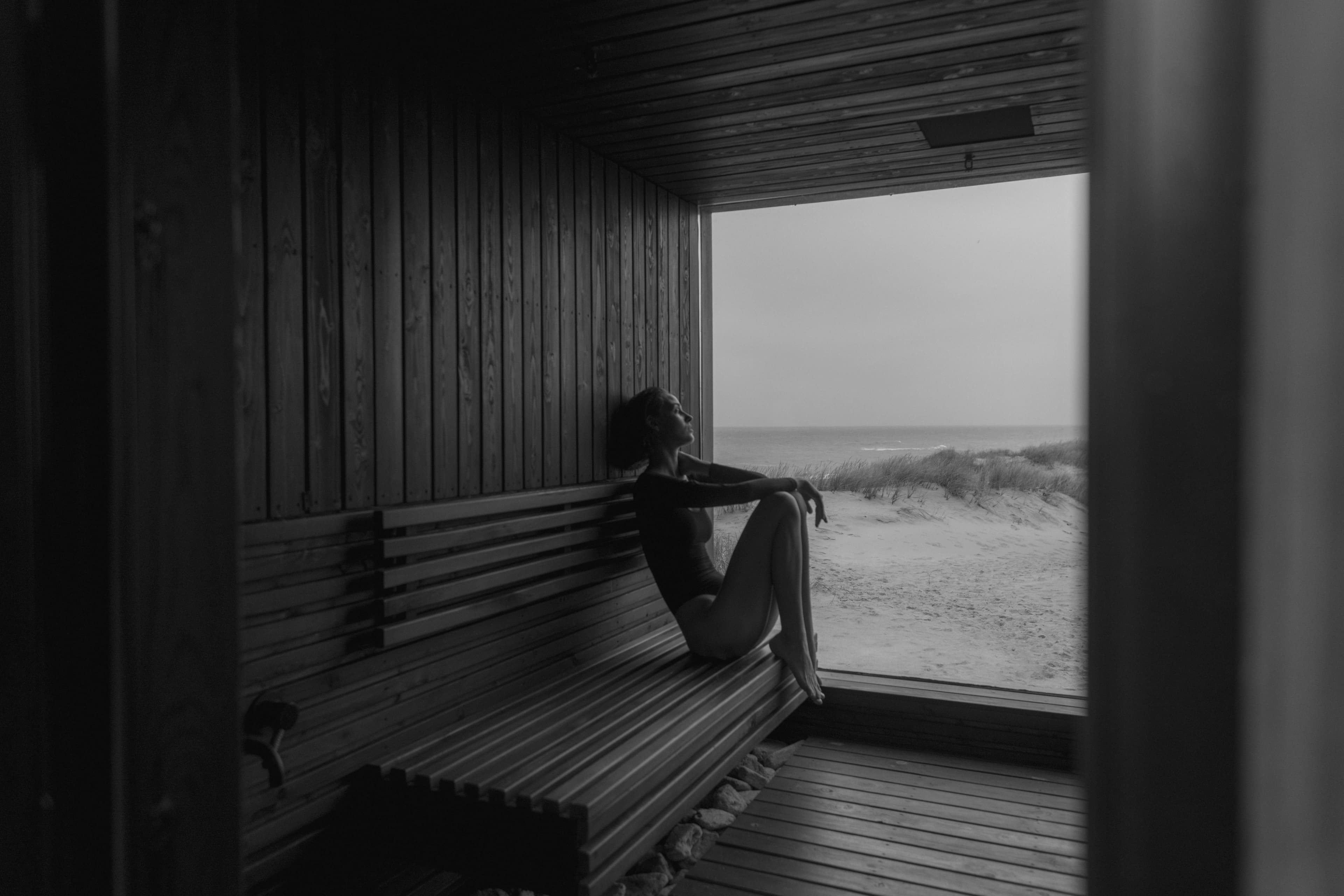 A timber-lined sauna interior in low warm light, bench and stones visible through rising steam