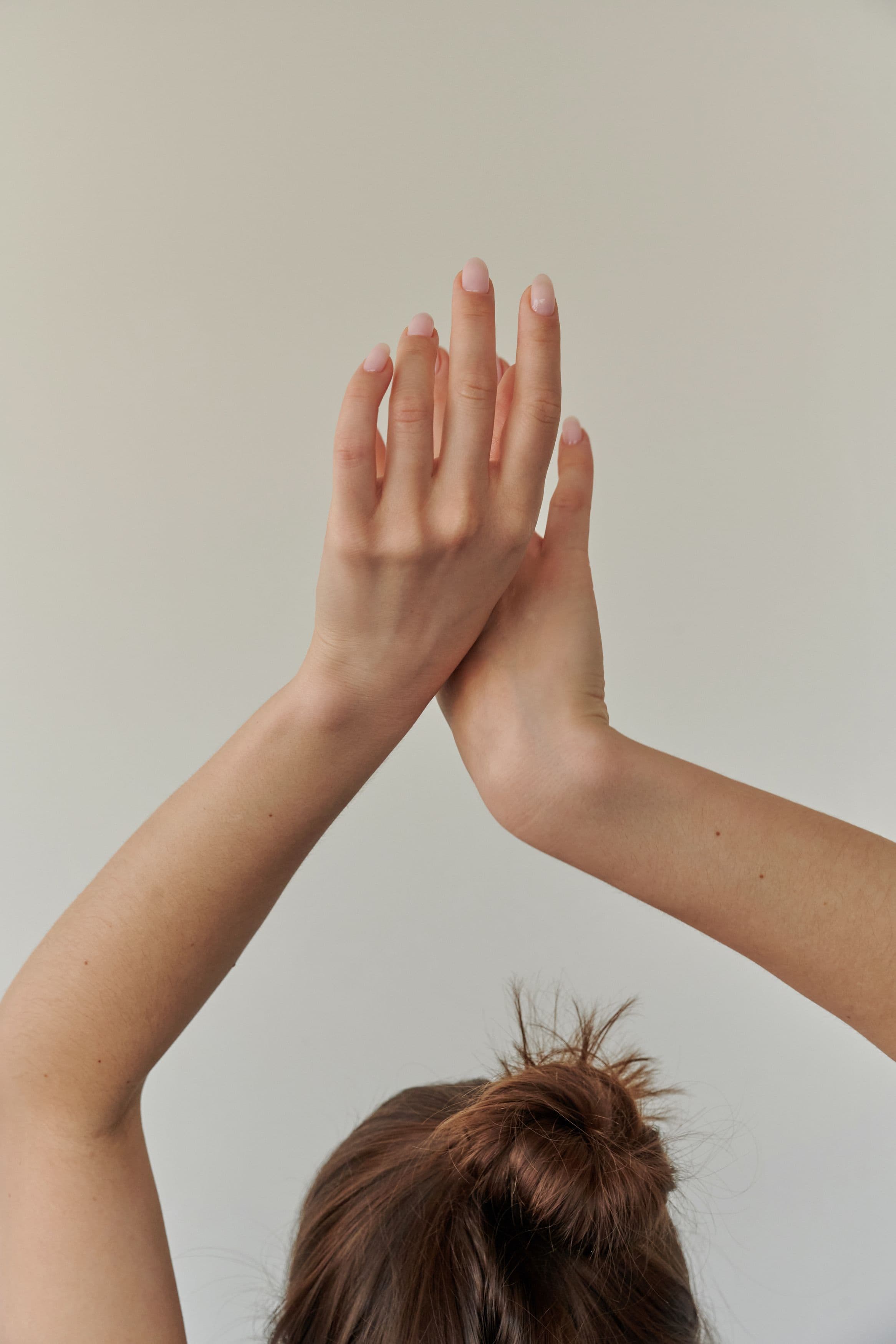 Hands resting on a linen napkin, with short, softly rounded nails in a sheer pink polish