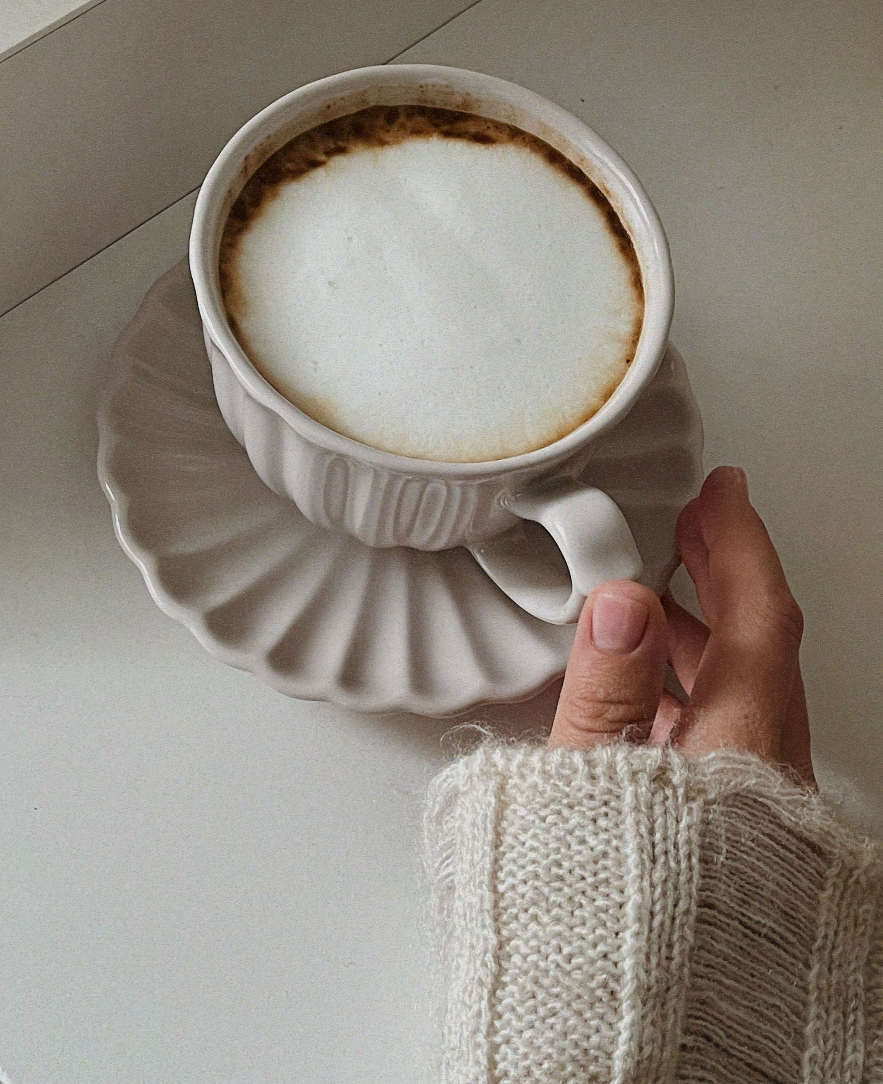 Coffee being poured by hand into a well-used mug on a kitchen counter