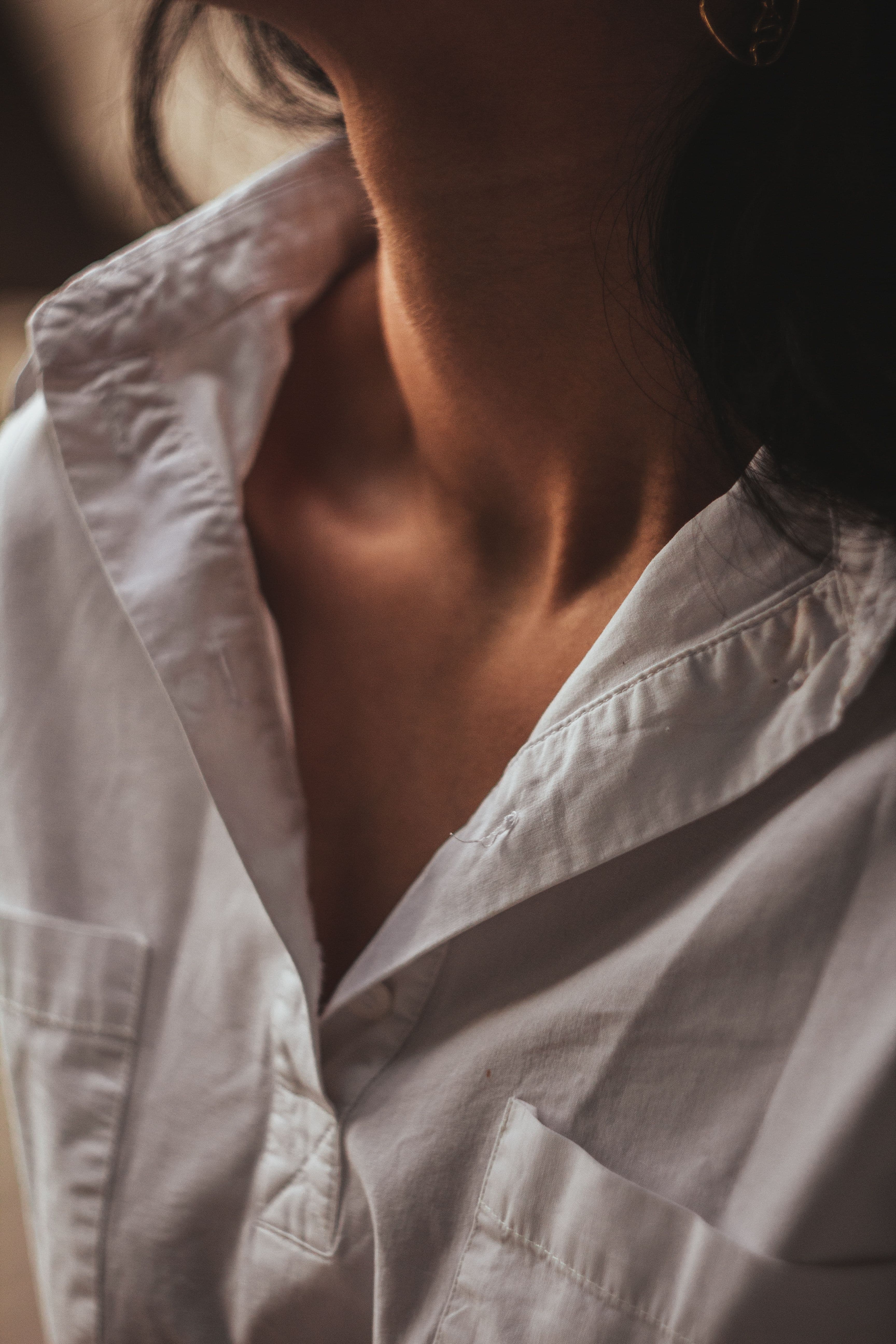 Close detail of a white cotton shirt collar, placket and buttons, showing the weave and stitching