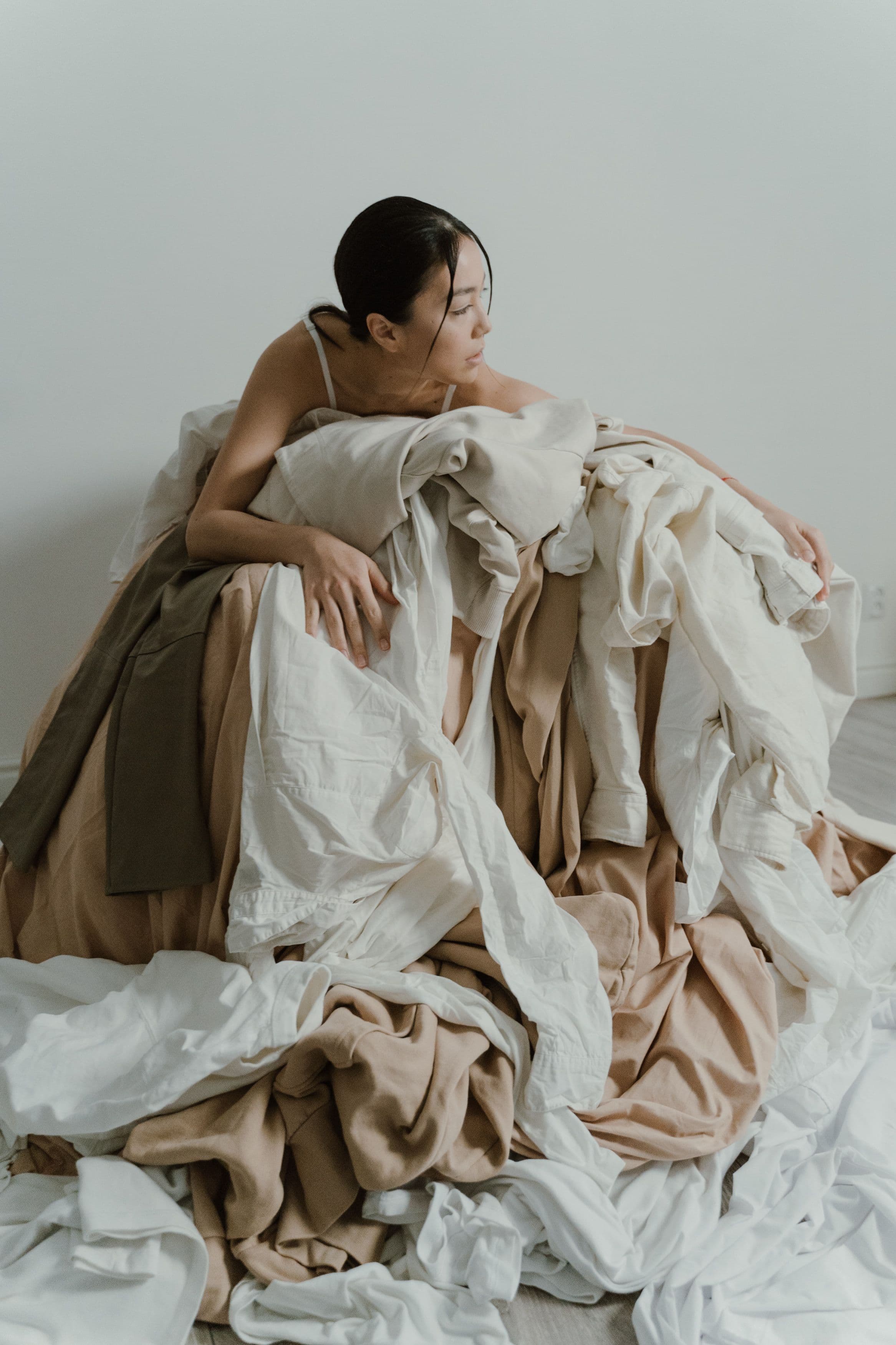 A jacket, a skirt and a blouse laid over the end of a bed, tried on and left
